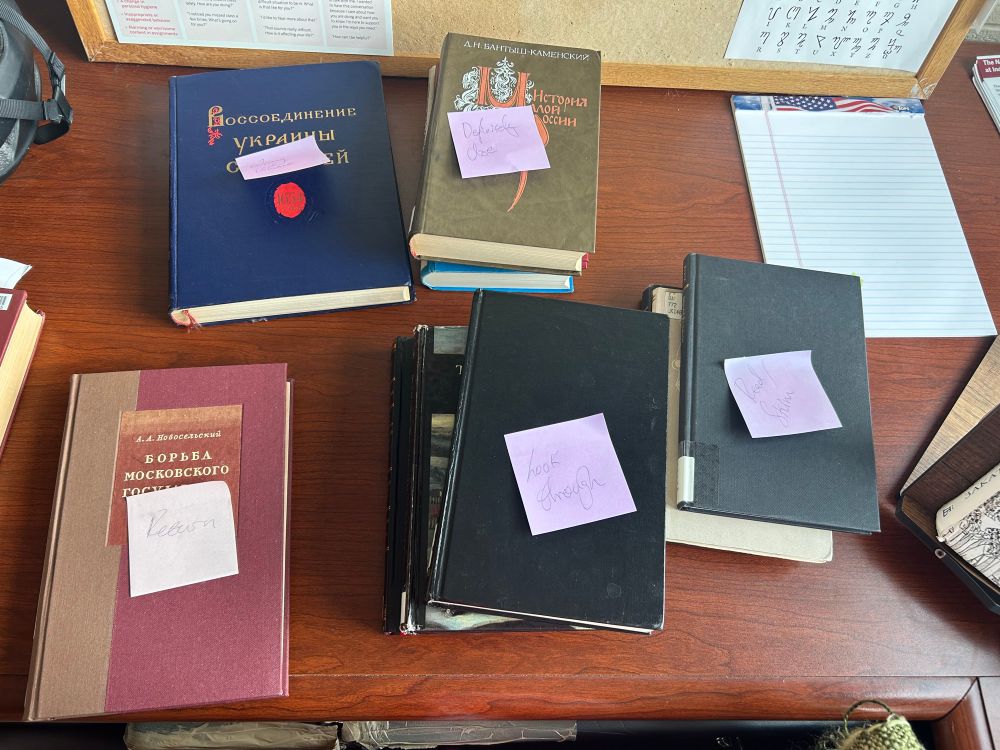 Piles of books with post it notes on them