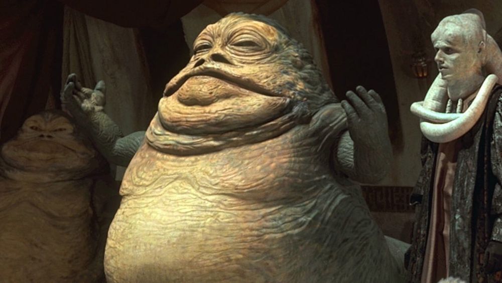 Jabba thr Hutt from Star Wars with another one of his species on the left and some pale tentacle-headed sycophant on the right