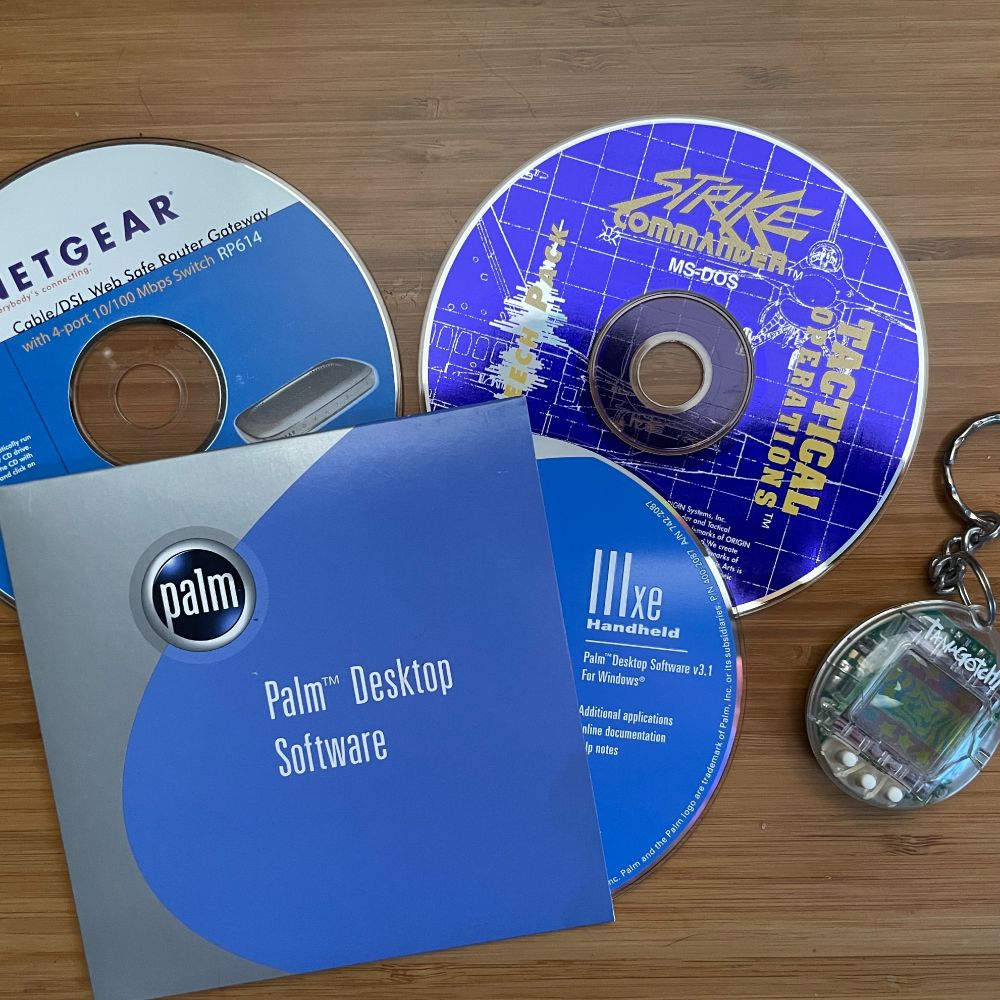 Strike Commander for MS-DOS, a Tamagotchi, a Netgear CD, and Palm Desktop software for a Palm IIIxe handheld