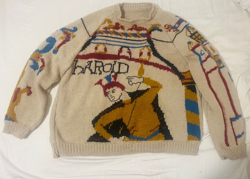 Beige jumper on a white background, the front panel shows harold holding a spear under an archway (scenes from bayeux tapestry)
