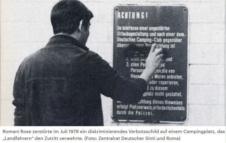 Ein Foto wie Romani Rose ein diskrminierendes Verbotsschild auf einem Campingplatz unkenntlich macht.