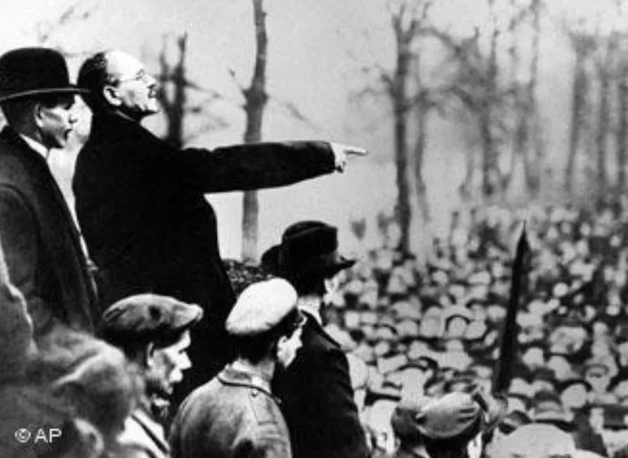 Ein s/w Foto von Liebknecht der gestikulierend zu den Massen spricht.