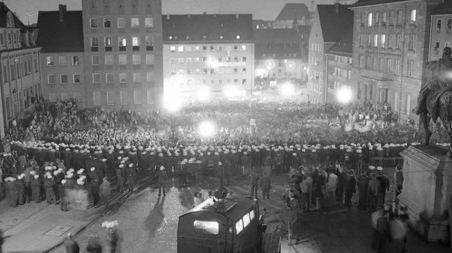 Schwarz-Weiss Foto der großen Kundgebung aus der Vogelperspektive. Vor den tausenden Demonstrant*innen stehen mehrere Polizeireihen.