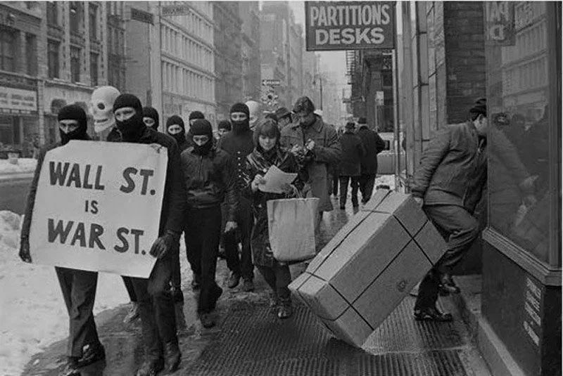 Black clothed protesters with balaclavas marching threw Manhattan with the sign "Wall St. is War St." 