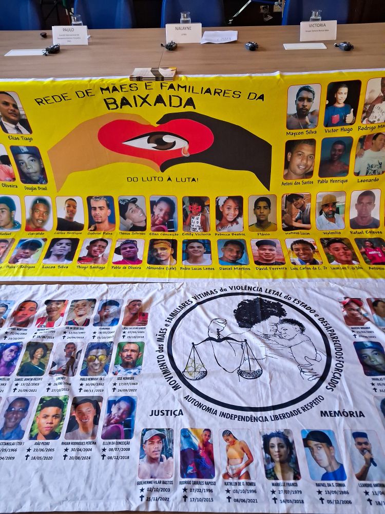 A imagem mostra dois cartazes. No primeiro está escrito "Rede Mães e Familiares da Baixada. Do luto à luta". O fundo dele é amarelo e há um desenho de uma mão parda e outra negra que formam um coração com um olho chorando em seu centro. Abaixo do primeiro cartaz, há o do Movimento Mães e Familiares Vítimas da Violência Letal do Estado e Desaparecidos Forçados. O símbolo desse grupo é uma mãe negra que segura uma balança da justiça na mão direita e um bebê na esquerda. Abaixo do símbolo está escrito "Autonomia, independência, liberdade, respeito". Este cartaz tem o fundo branco e mais fotos de vítimas da violência do estado, com suas datas de nascimento e óbito abaixo de cada foto.