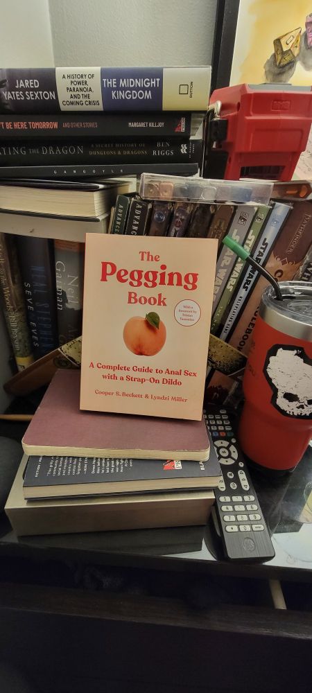 A picture of The Pegging Book by Cooper S. Beckett and Lyndzi Miller on top of a dresser strewn with books and sundries. 