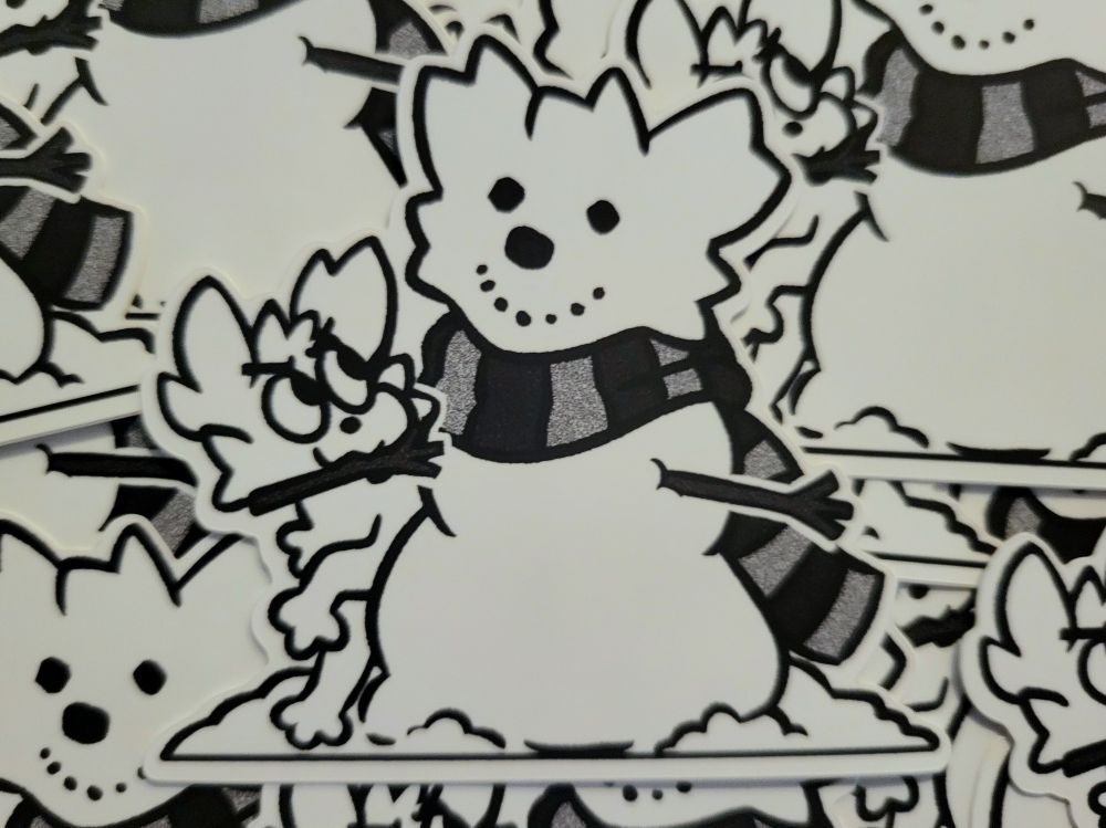 Photo of multiple stickers displayed on top of each other. The sticker's design is a B/W drawing of Pippi making a snowman with their own face on it; a large, striped scarf hangs around its neck while Pippi looks for a good place to stick the snowman's second arm into its body. Little bits of compacted snow are positioned to resemble their cheeks and large ears.