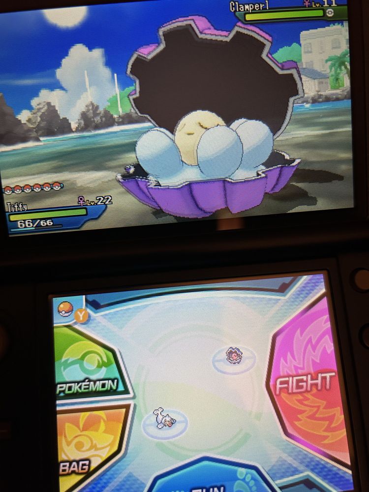 A photo of a handheld game console Nintendo 3DS, showing a Pokemon game on the screens