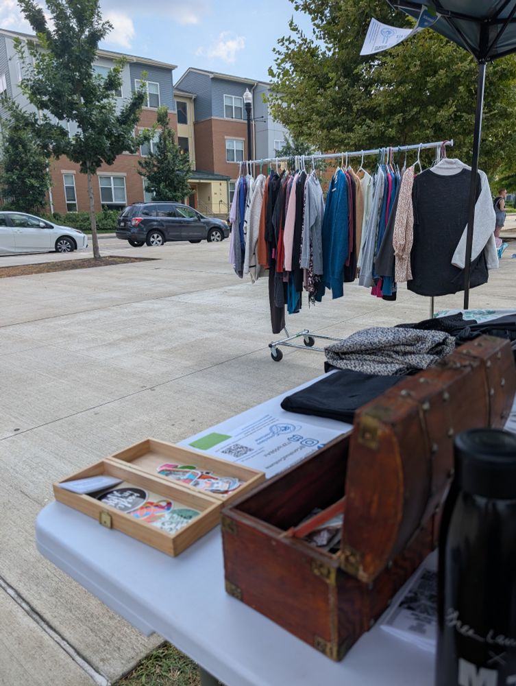 Clothing rack on a sidewalk with a table in the foreground 
