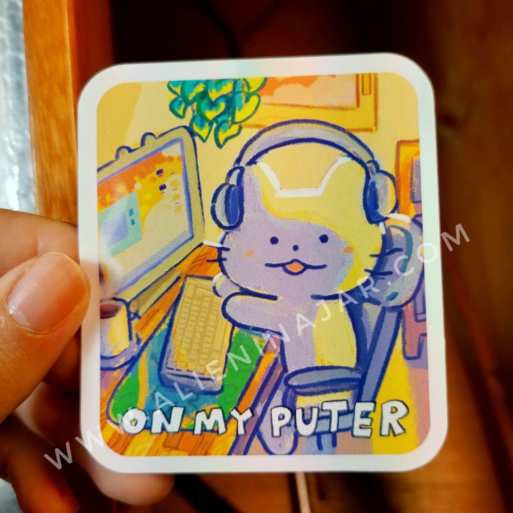 Sticker of a cat on a desk with headphones, text says: on my puter 