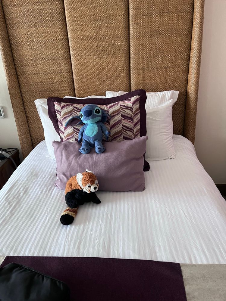 Red panda and stitch plushies positioned carefully on a newly-made bed.