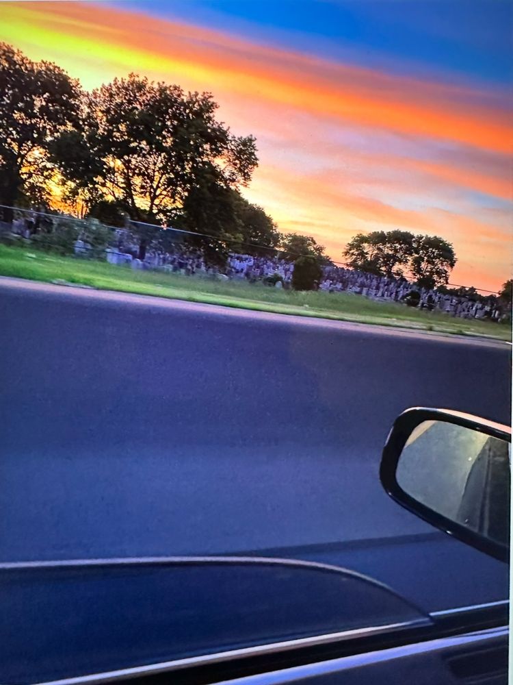 Photo by Dawn Berkoski of a car speeding past a cemetery.View is from the driver’s perspective, looking out the side window. 