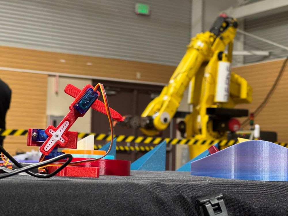 A toy robot arm appears to be reaching for a real one. 