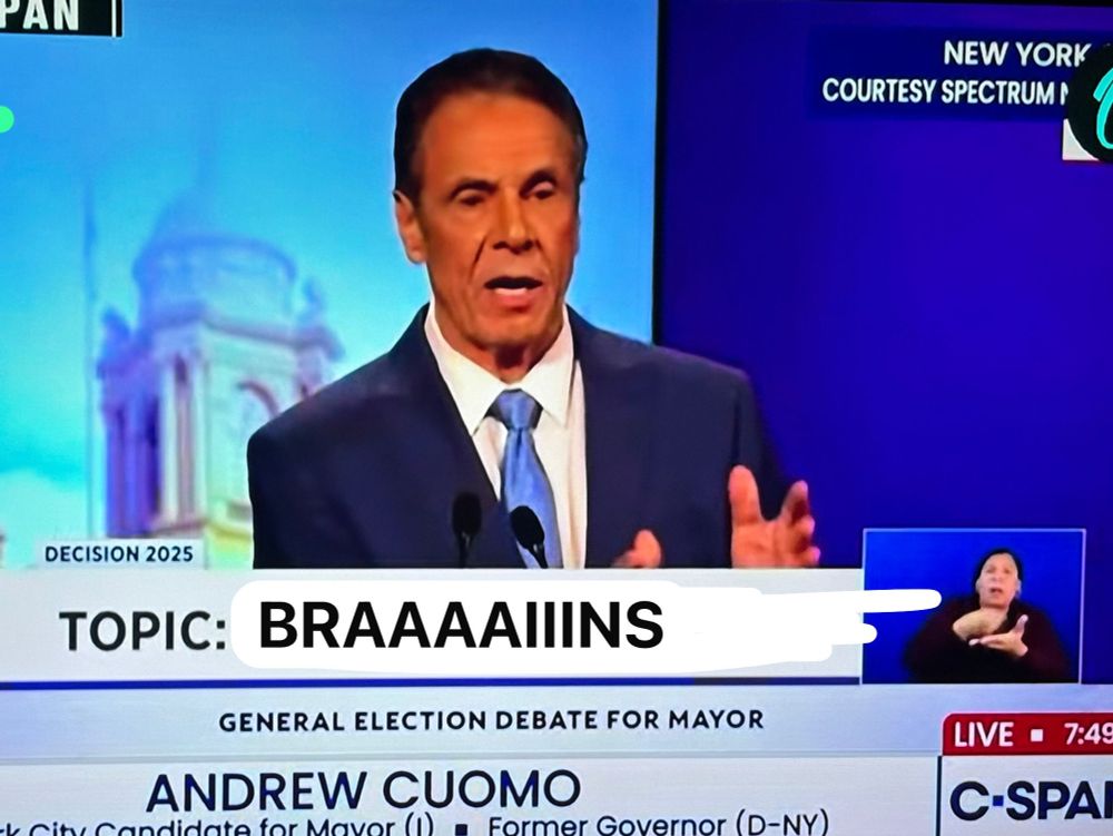 Andrew Cuomo with TV make up strongly emphasising his fake tan. A Photoshop Chevron shows the caption: topic: BRAAAAAIIINS”