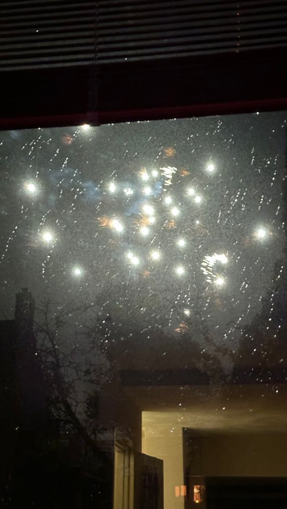 Fireworks through a rain-spattered window. 
