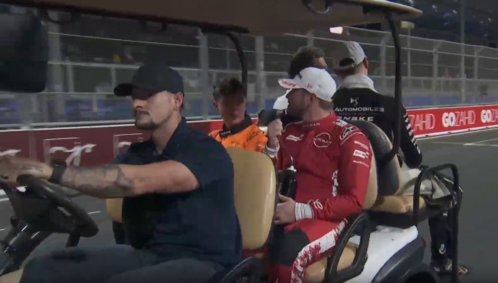 Oliver Rowland and Taylor Barnard in a golf buggy on the way to the podium chatting.