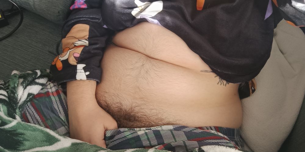 Photo from above of my lightly hairy belly and pubic hair peeking out above my pajama pants. I'm wearing a black soft Pokémon pajama shirt.
