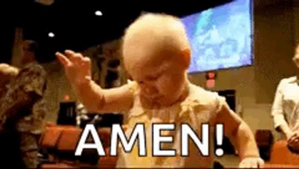 a baby is standing in front of a large screen with the word amen written on it .