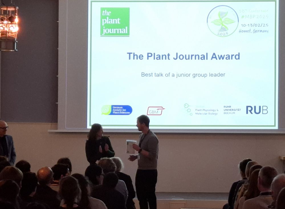 Tonni Grube Andersen on stage at MBP2025, receiving the Plant Journal Best talk award from EiC Katherine Denby.