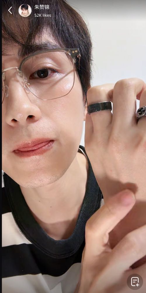 Screenshot from Zhu Zanjin's live. He is now closer to the camera, holding up his hand to show off his ring. The tip of his tongue is peeking out from between his lips. There's a tiny bit of stubble visible in his chin and upper lip. He is altogether deadly. RIP us all.