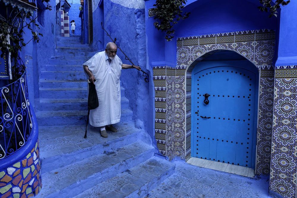 An elderly man walks down the stairs in the Medina of the northwestern Moroccan city of Chefchaouen on August 14, 2025, known for its buildings in shades of blue. (Photo by Abdel Majid Bziouat/AFP)