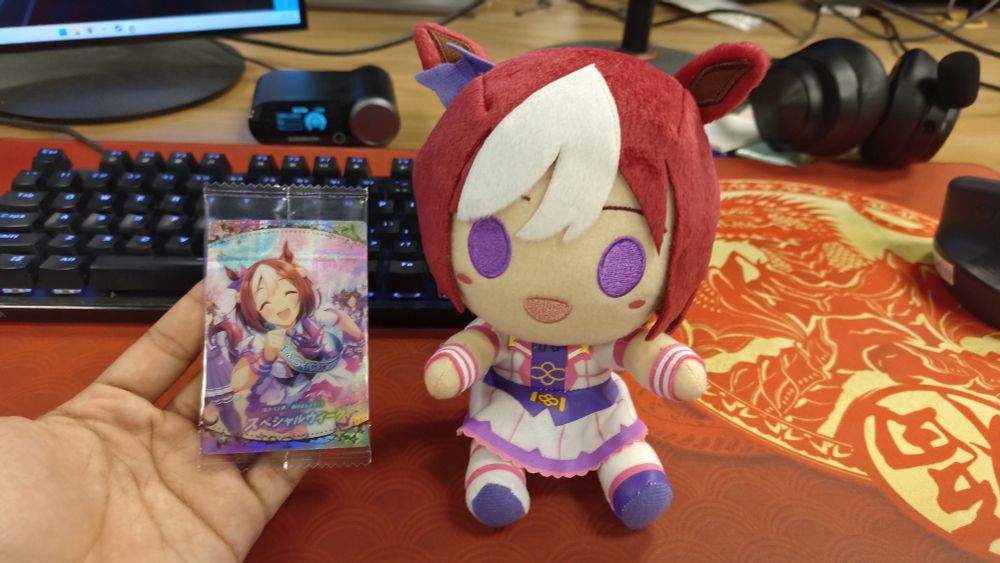 A physical version of Special Week's SSR guts card and a Special Week plushie.