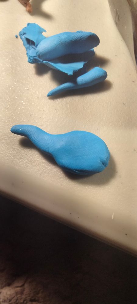 A ball of clay with a head and body with its tail and the rest of it above.

