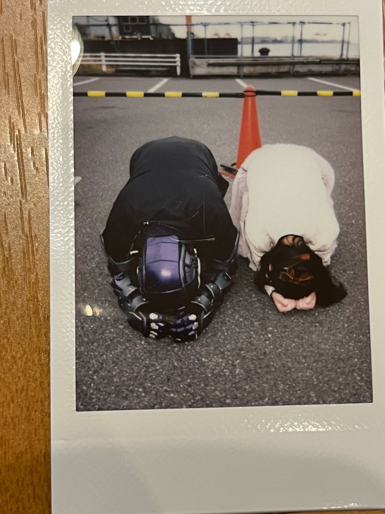 チェキの画像。左にダンゴムシマンさん、右にわたし。2人で地面に丸まってダンゴムシのポーズをとっている。