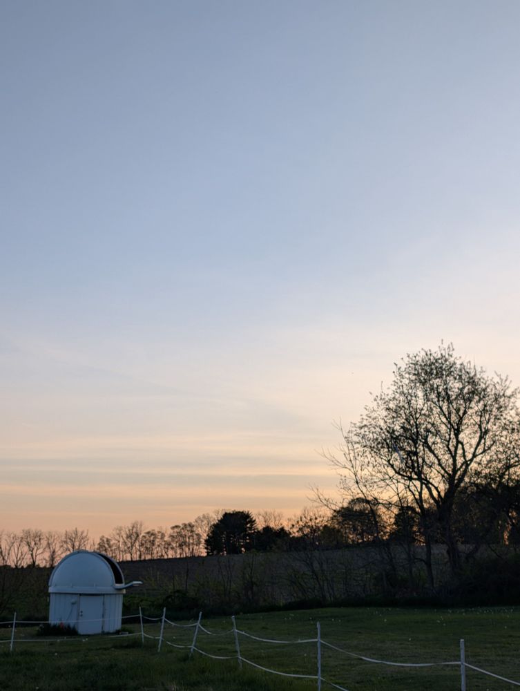 It's a picture of mostly sky. It's just after sunset and there are thin clouds in bands low on the horizon. There's an observatory with the shutter open in the lower left-hand corner.