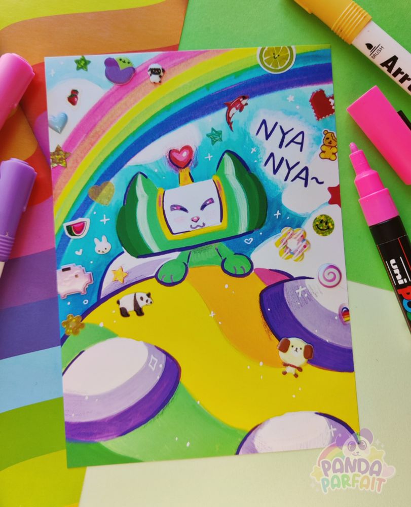 Photo of a print against a scrapbook paper background. The print is of the Katamari prince, but with cat ears and nose. He is pushing a giant rainbow Katamari and surrounded by stickers 