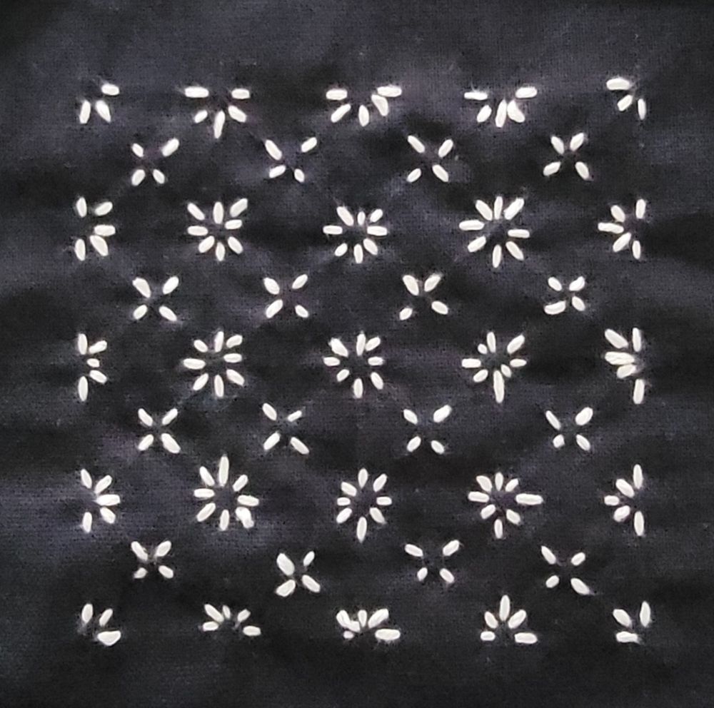 White stitches on navy blue cloth in the sashiko pattern "hanazashi" or flower stitch