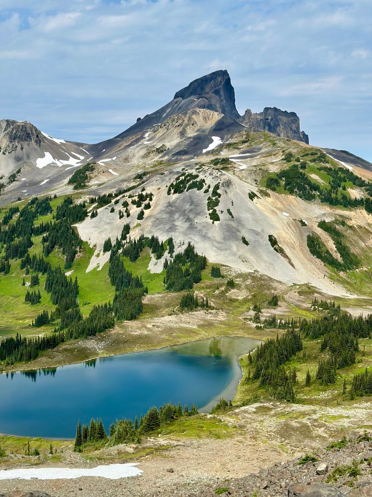 The dramatic peak of the Black Tusk towering over a tree-spotted landscape with a small pond in the foreground