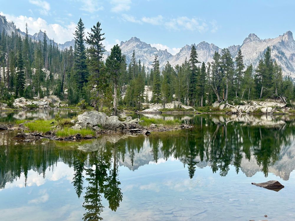 The Sawtooth Mountains and evergreen trees reflected in a mountain lake