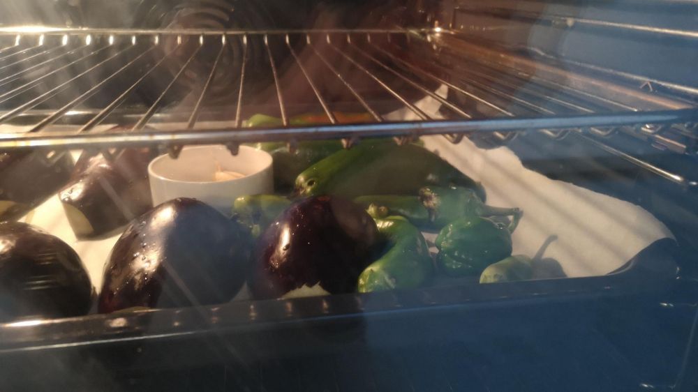 Vue de l'intérieur d'un four avec des aubergines, des poivrons et de l'ail.