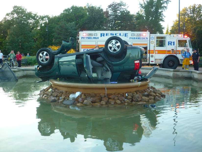 a wrecked SUV flipped upside down in the center of the Highland Park fountain in Pittsburgh