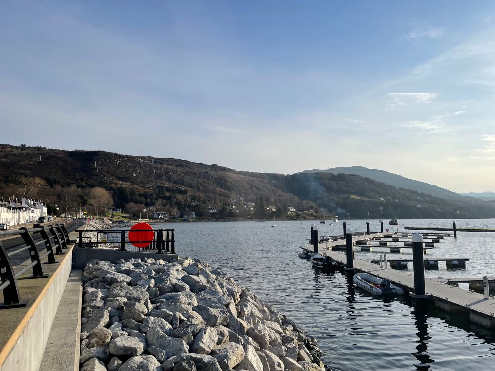 Lochside walkway and promenade at Ullapool with mountains and hills behind 