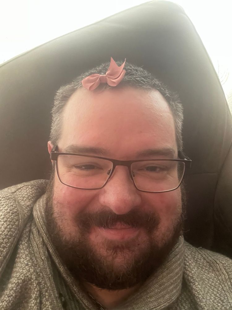 Me; a large man with a beard and glasses and with a bow in my hair