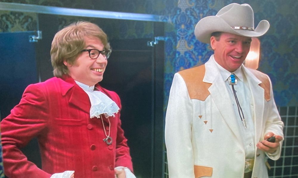 Austin Powers standing next to some guy in a cowboy outfit who is the most supportive and thoughtful man in Las Vegas 