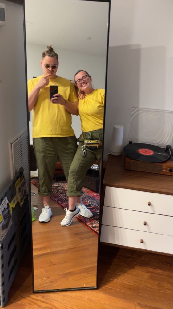Mirror selfie of me and my gf wearing matching yellow shirts and green pants and white sneakers 