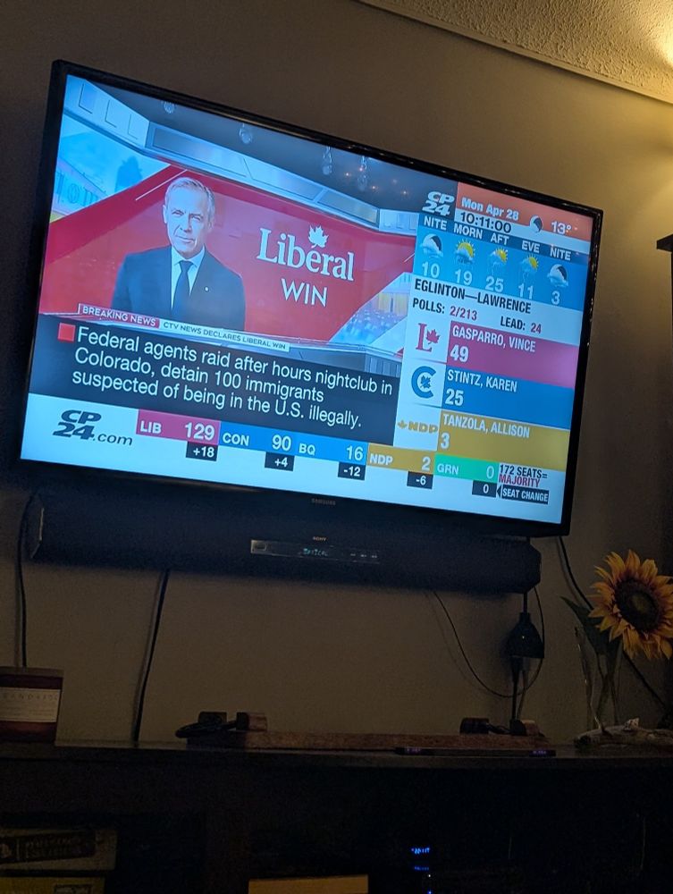 A TV screen displays "Liberal win" with a photo of Mark Carney.