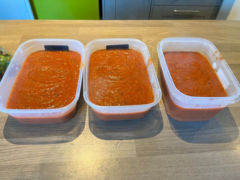 3 Tupperware containers filled with homemade tomato pasta sauce.