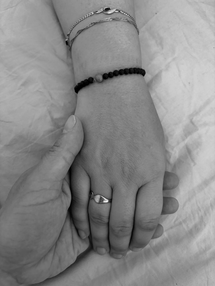 Photo en noir et blanc 
Une femme portant une bague au doigt et des bracelets au poignet est posée sur une autre main