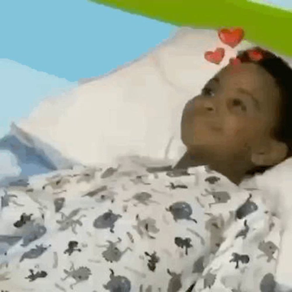 a young boy is laying in a hospital bed with a blanket on his head .