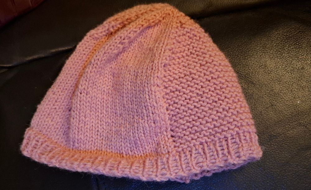 Rose pink, knitted toddler hat with one side done in stocking stitch and one side in garter.