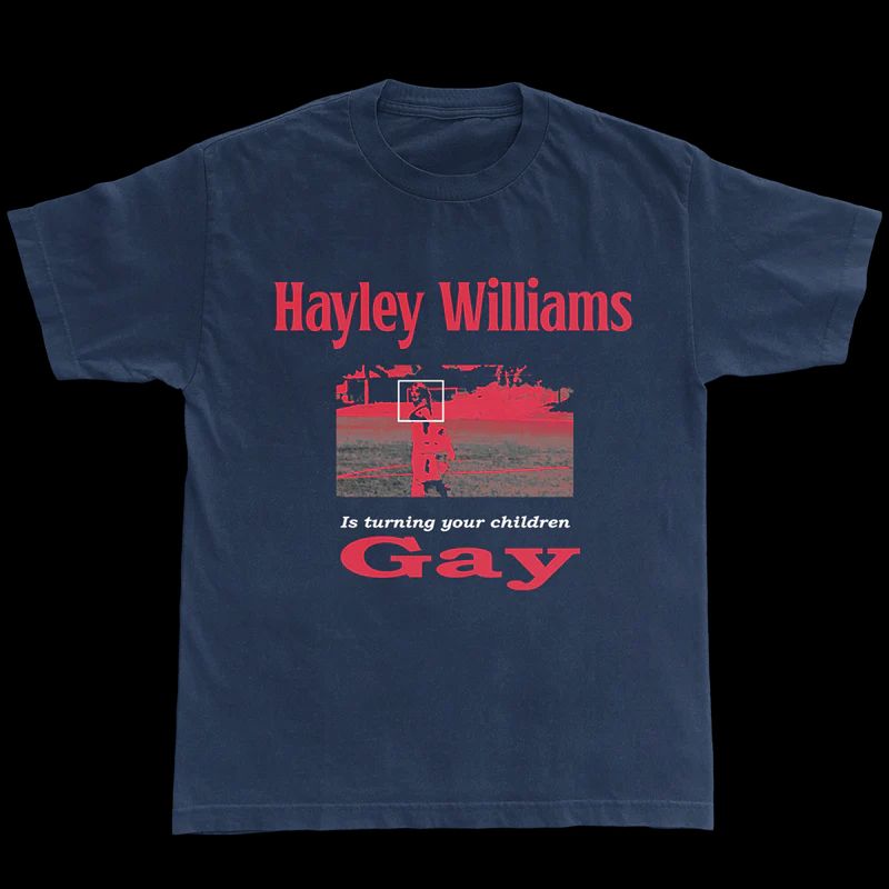 dark blue t-shirt with red text that says "HAYLEY WILLIAMS IS TURNING YOUR CHILDREN GAY" with a surveillance photo of hayley williams that has a white square around her face like an FBI investigation photo