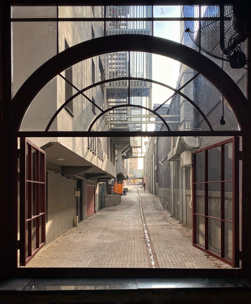 A symmetrical view through a large window into a wide alley. 