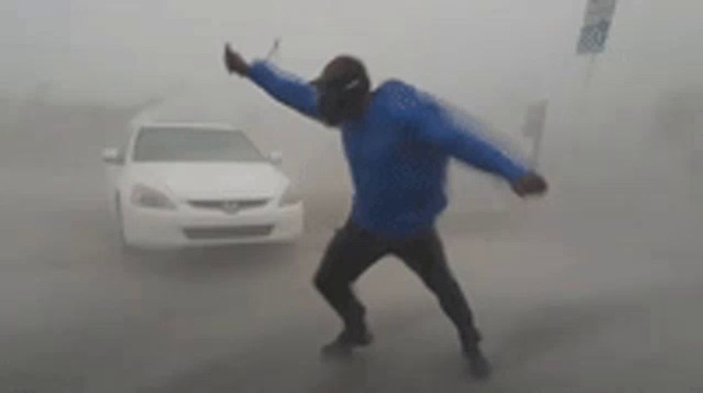 a man in a blue jacket is standing in front of a car in a foggy street .