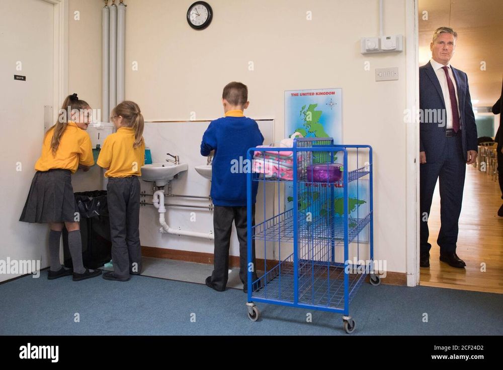 Keir Starmer looking menacing while small children wash their hands 