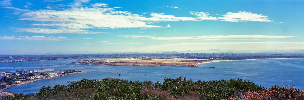 A 6x17 panorama image of San Diego, California. North Island, home to the US Military, is prominently featured in the middle of the image. The Hotel del Coronado and Downtown San Diego can been seen in the distance. 