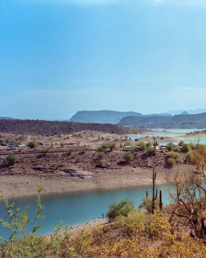 A cropped photo of the previous panoramic. In this photo, the lake is seen winding through the desert landscape, with tall mountains in the background. 